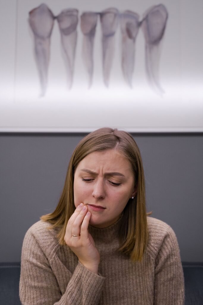 A concerned adult woman with a toothache sits in a dental office.