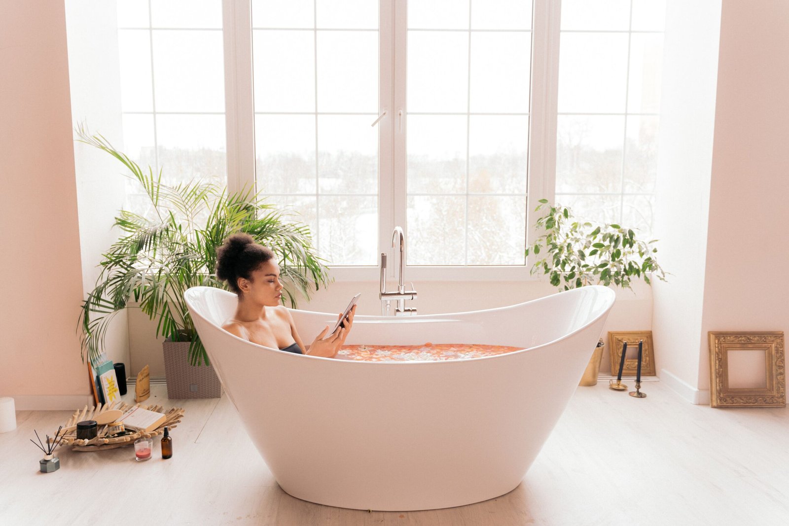 A woman enjoying self-care in a modern bathtub surrounded by plants, creating a serene atmosphere.