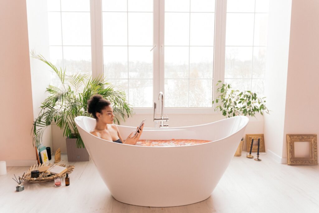 A woman enjoying self-care in a modern bathtub surrounded by plants, creating a serene atmosphere.
