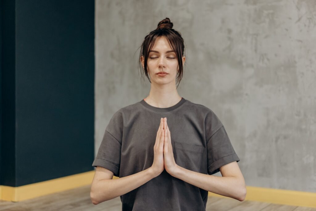 A woman meditating indoors with eyes closed, focusing on mindfulness and relaxation.