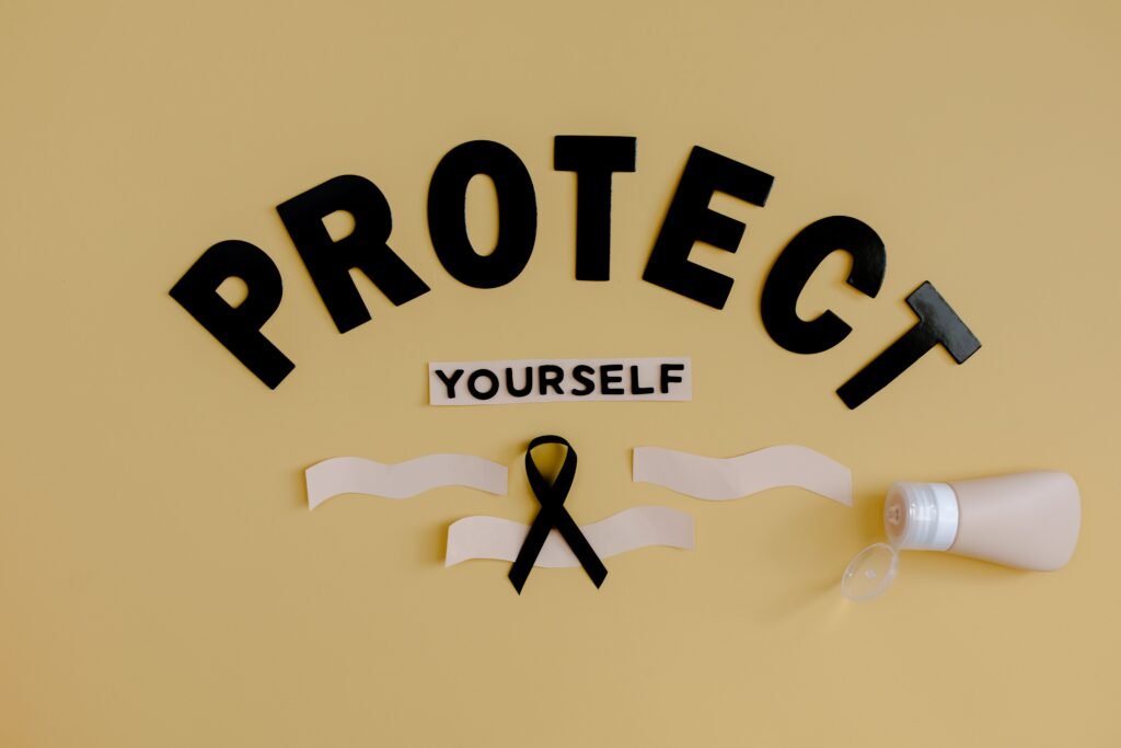 Top view of black ribbon representing melanoma placed on yellow background with Protect Yourself inscription and tube with antibacterial product