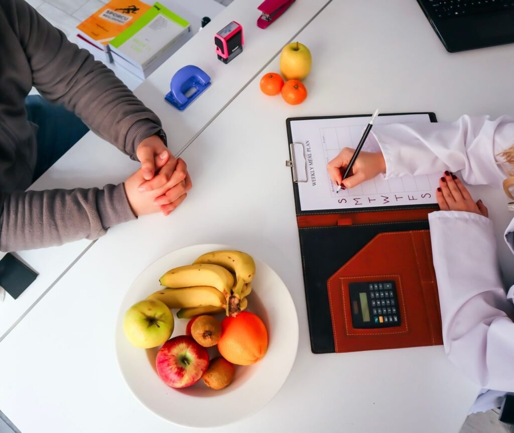 Person exercising with healthy food, dumbbells, yoga mat, and fresh fruits illustrating the importance of combining exercise with a balanced diet for healthy weight loss.