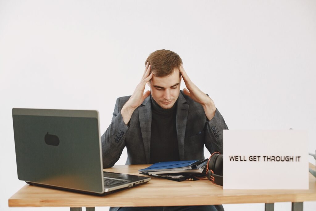Young man in home office feeling stressed, working during pandemic with motivational message by his side.