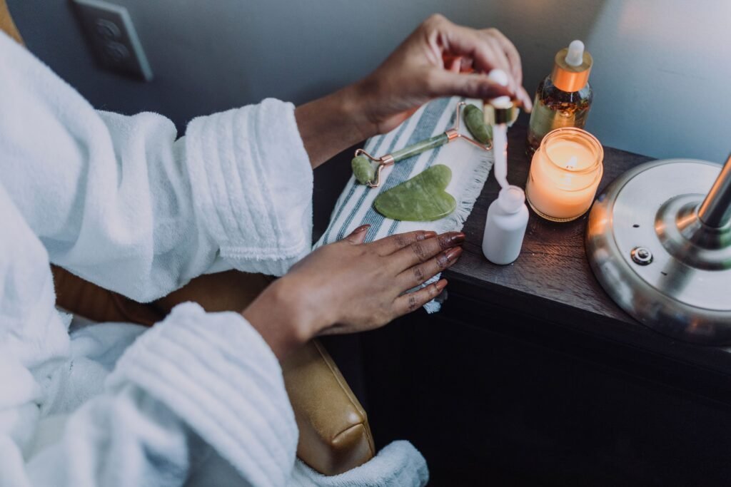 A cozy skincare setup featuring jade roller and candle for a soothing spa-like experience.