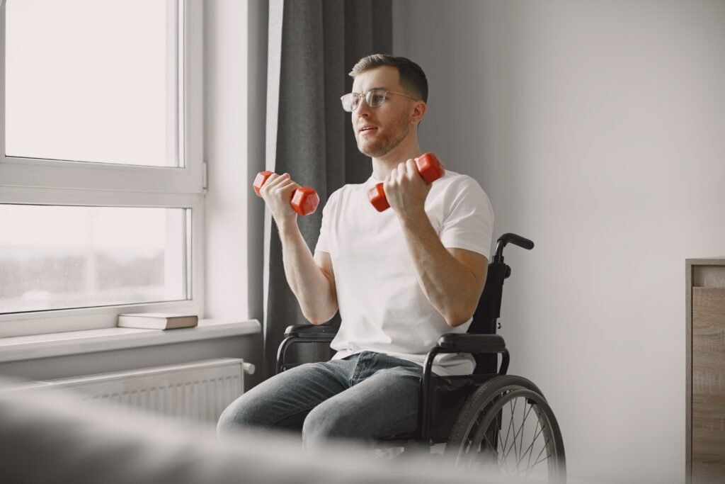 A man in a wheelchair doing exercises with dumbbells by a window indoors, promoting fitness.