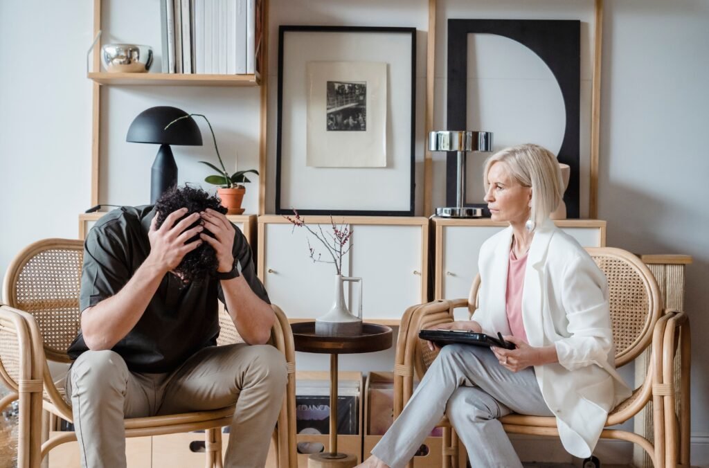 Professional therapy session with a stressed man and attentive female therapist in a modern office setting.